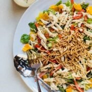 asian chicken salad on a white plate with serving utensils