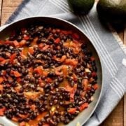black beans in a pan with tomatoes sitting on a blue cloth