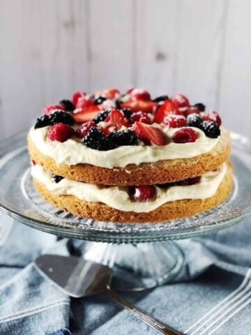 Italian berry cake on a cake stand on a blue table