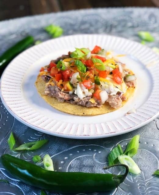 refried beans on a tostada with toppings on top.