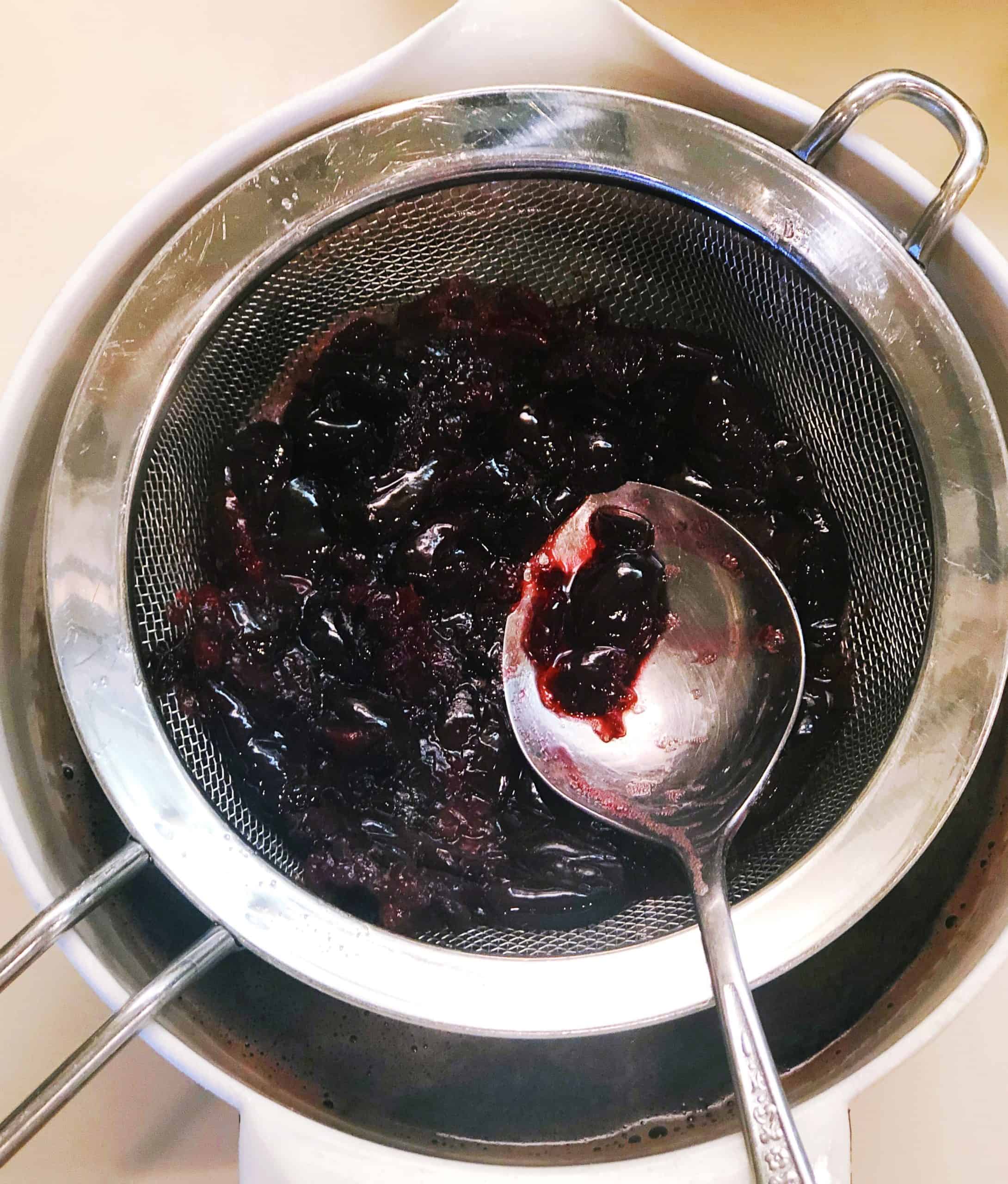 pressing out remaining cherry juice through strainer