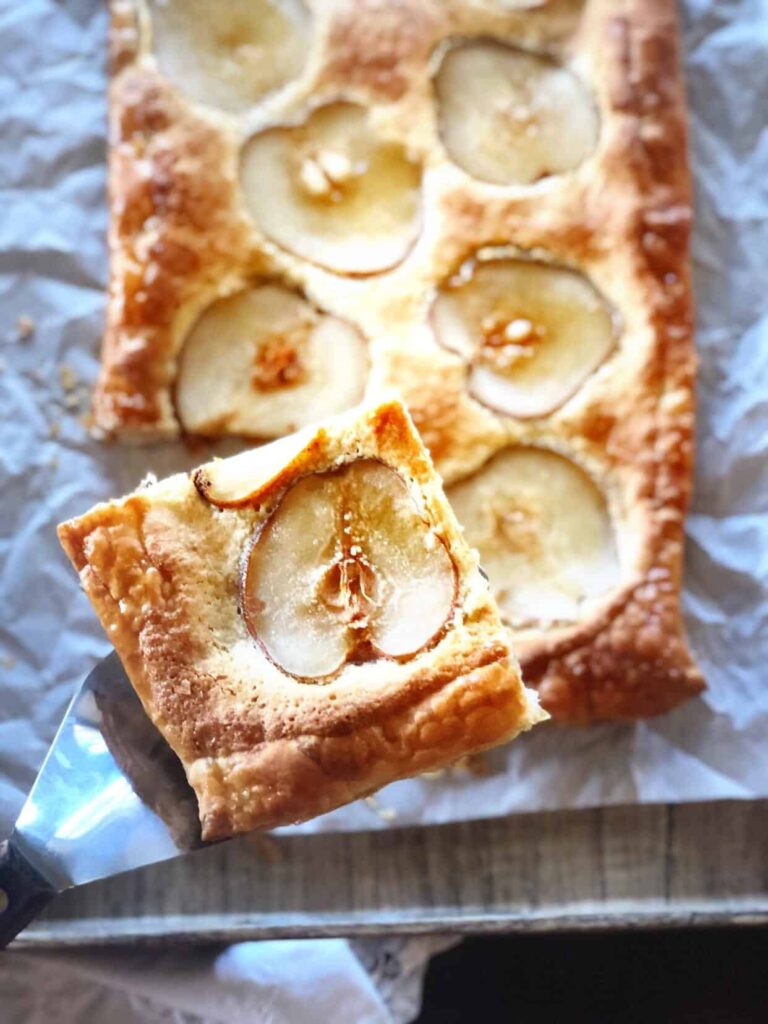 pear frangipane tart with a slice being taken from plate