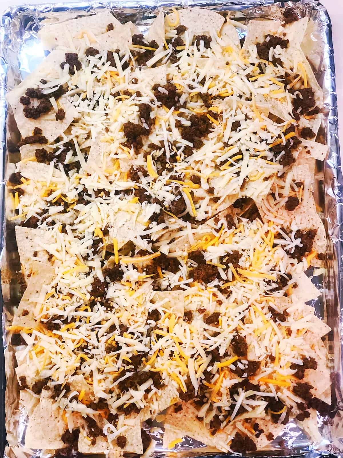adding cheese to loaded nachos