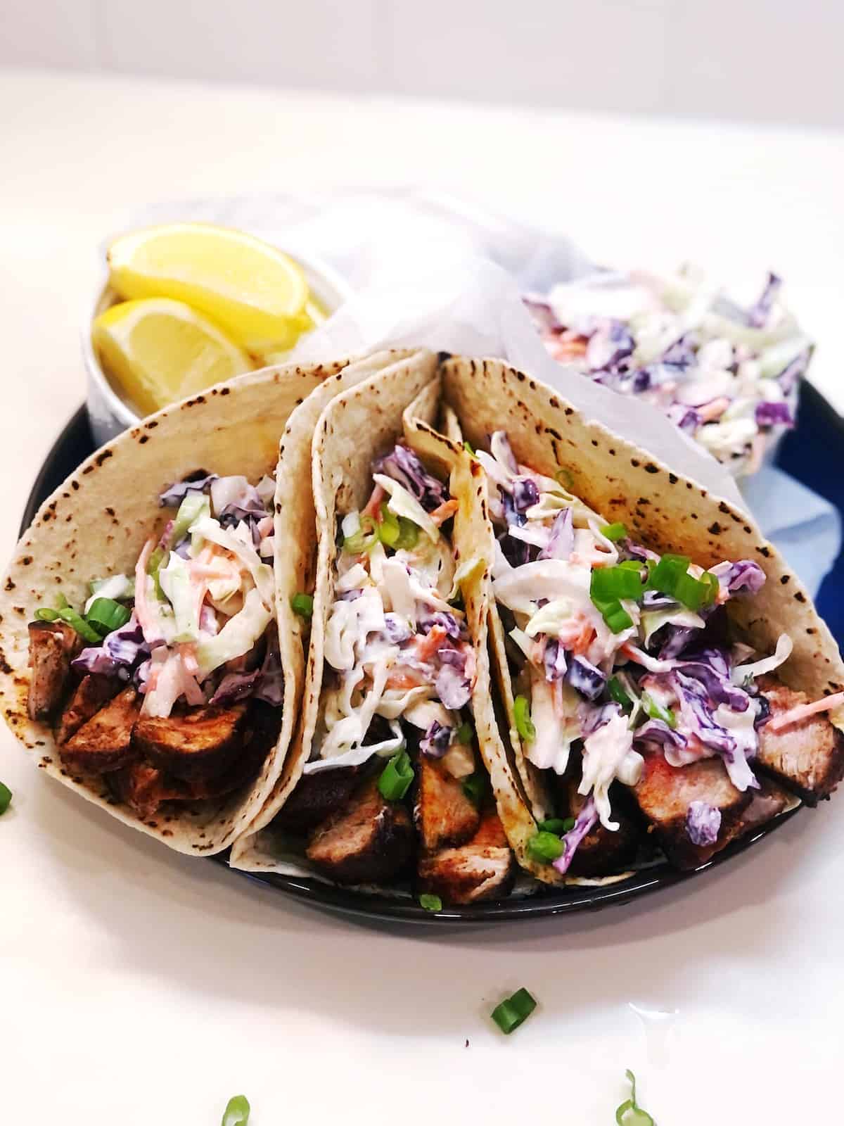 blackened tuna tacos on a plate with lemon wedges