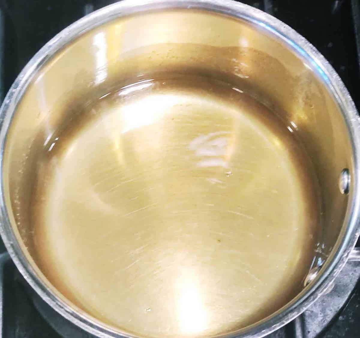 A stainless steel sauce pan with pear syrup at the bottom