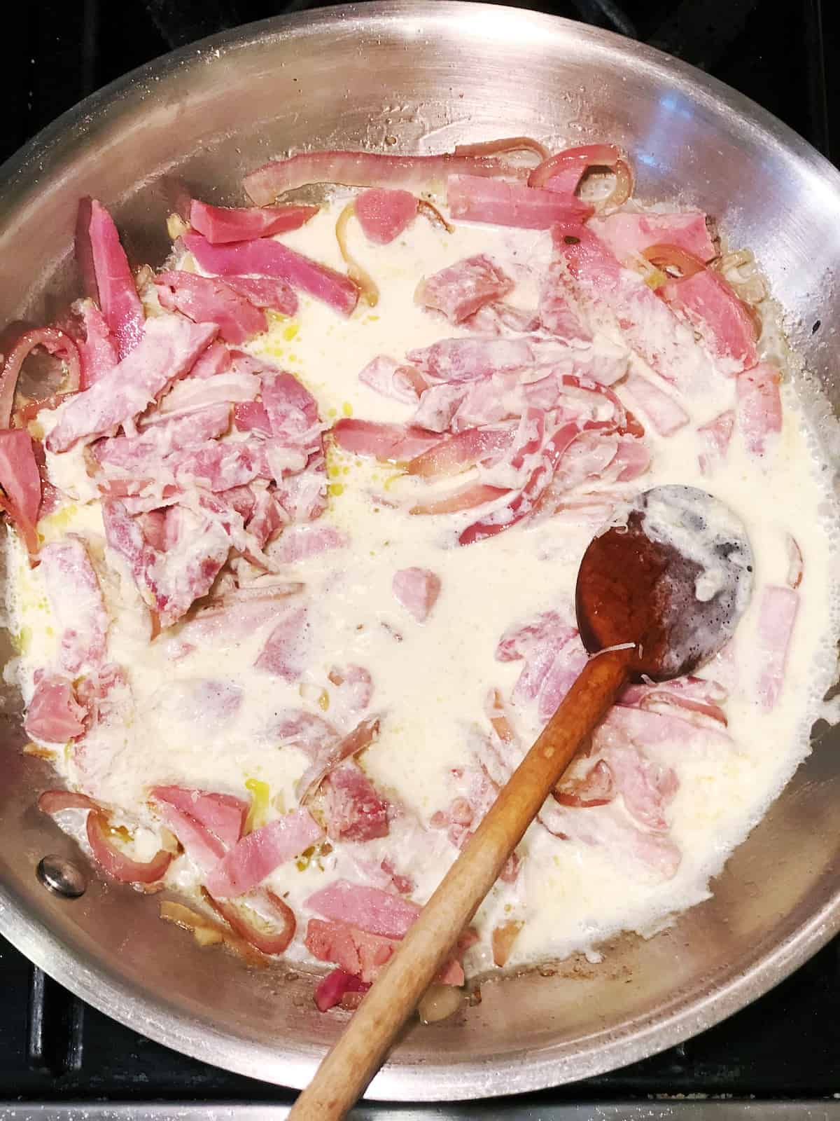 adding cream and parmesan to pasta