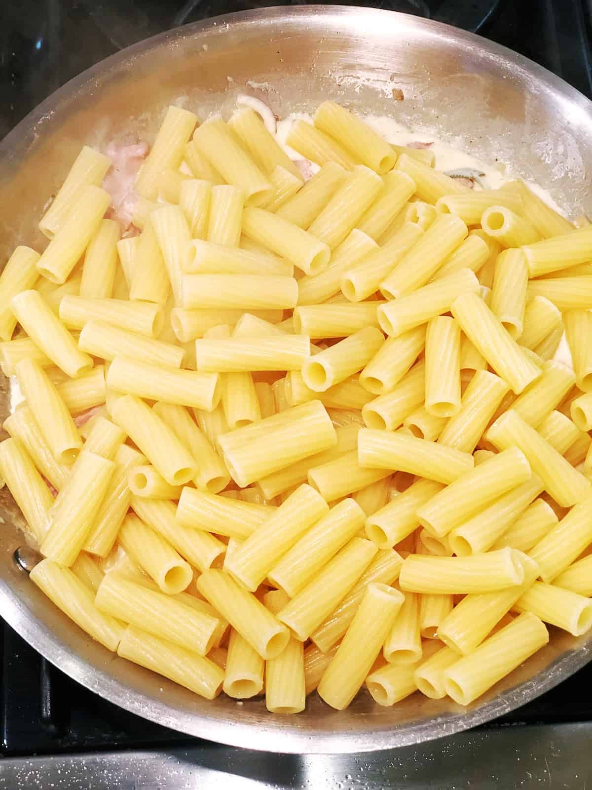 adding pasta to ham and cheese sauce