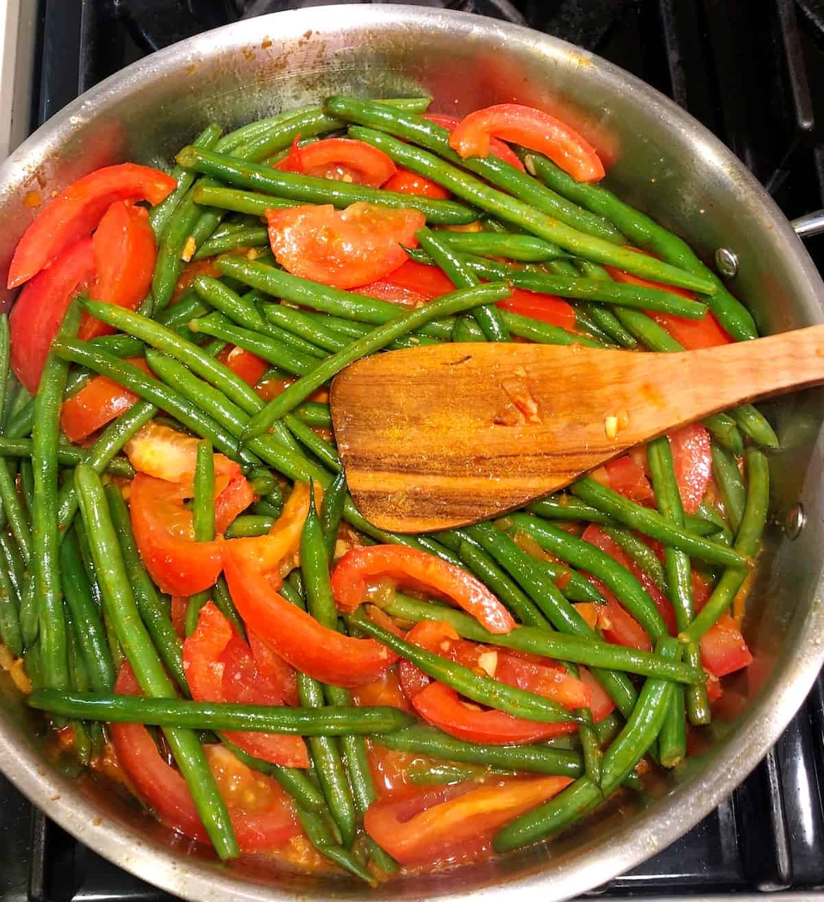 adding tomatoes to green beans