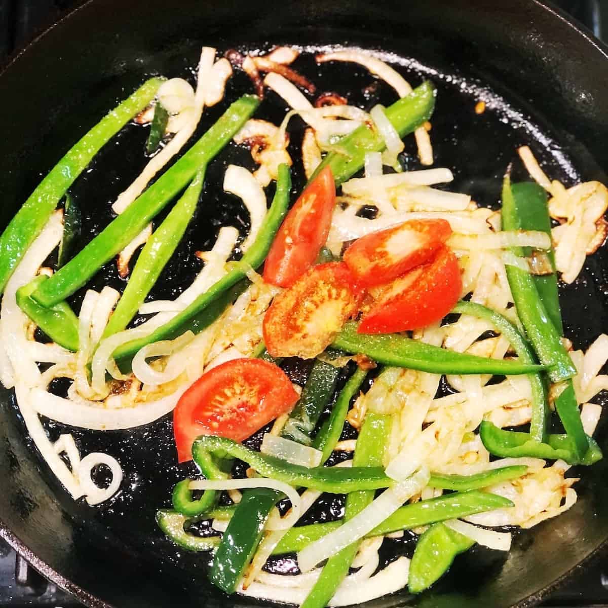 adding tomatoes to queso fundido