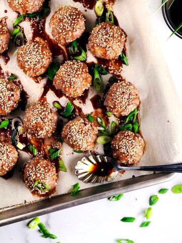 Asian Pork Meatballs on tray with sauce and scallions on top