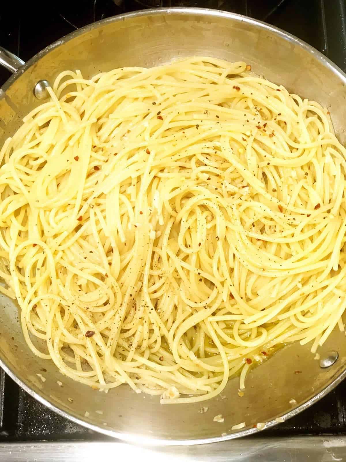 A pan of spaghetti cooking on a stove top.
