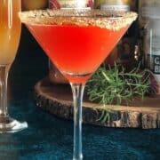An Aperol martini is sitting on top of a wooden board.