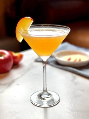 An apple cider martini with a slice of apple on top.