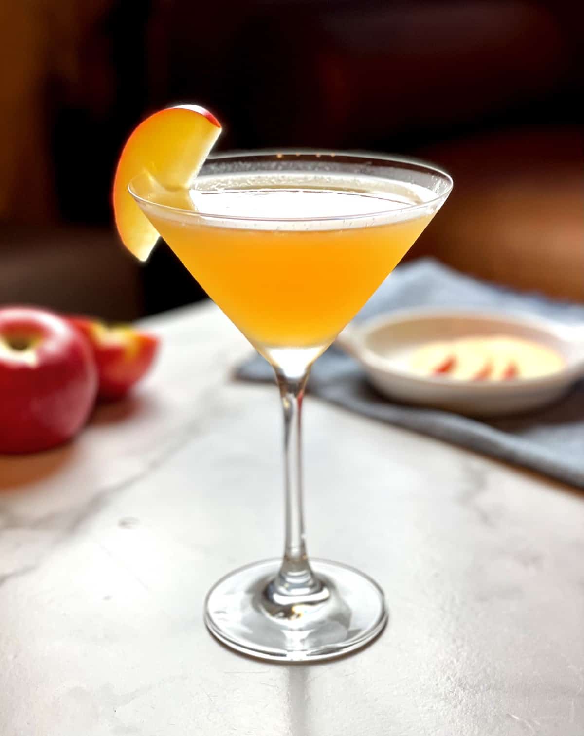 An apple cider martini with a slice of apple on top.