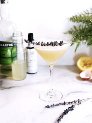 A martini with lemon juice and lavender sprigs.