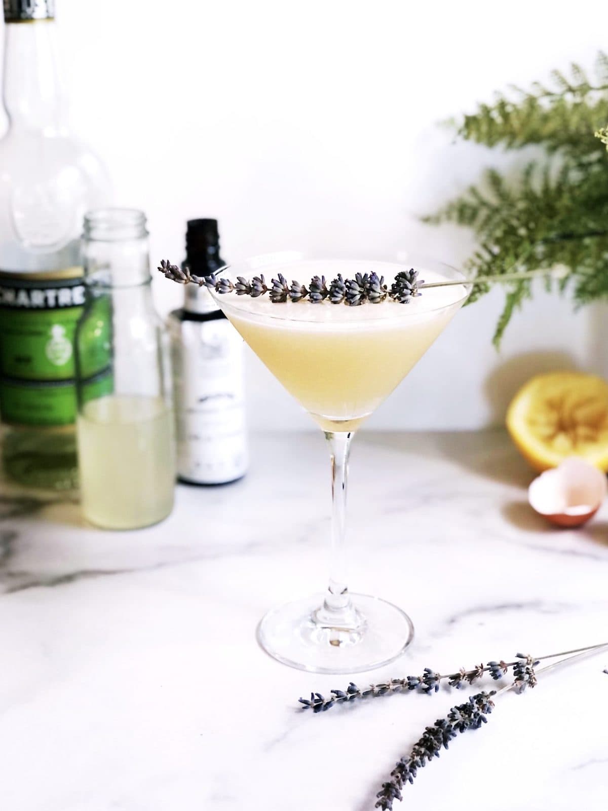 A martini with lemon juice and lavender sprigs.