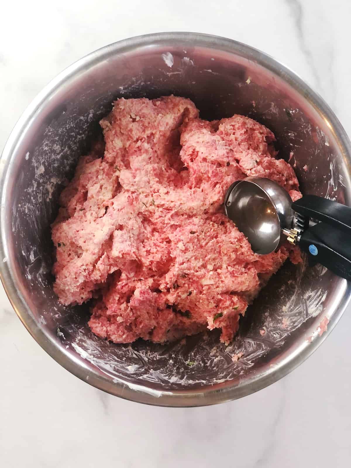 Ground beef in a bowl with a spoon.