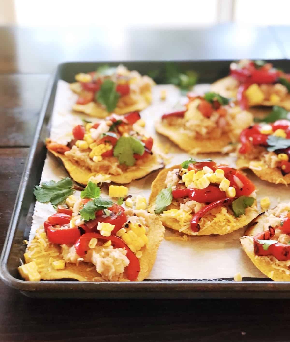 A tray of tostadas with vegetables and herbs on it.