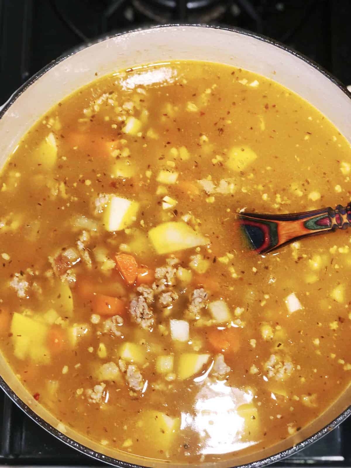 A pot of soup with meat and vegetables in it.