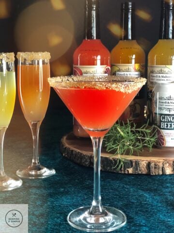 A trio of Aperol martinis sitting on top of a wooden board.
