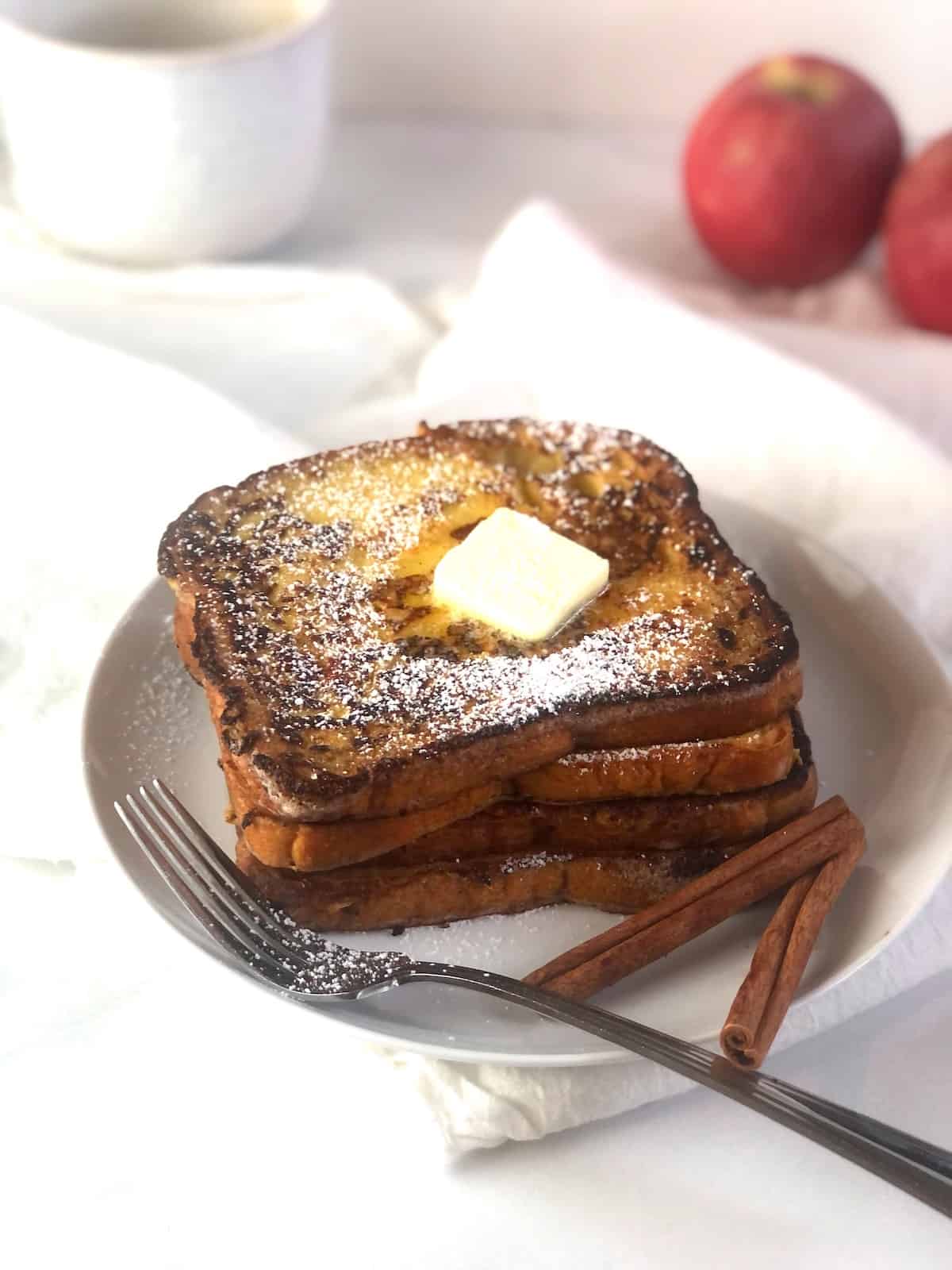 A plate of apple cider french toast topped with cinnamon and sugar.