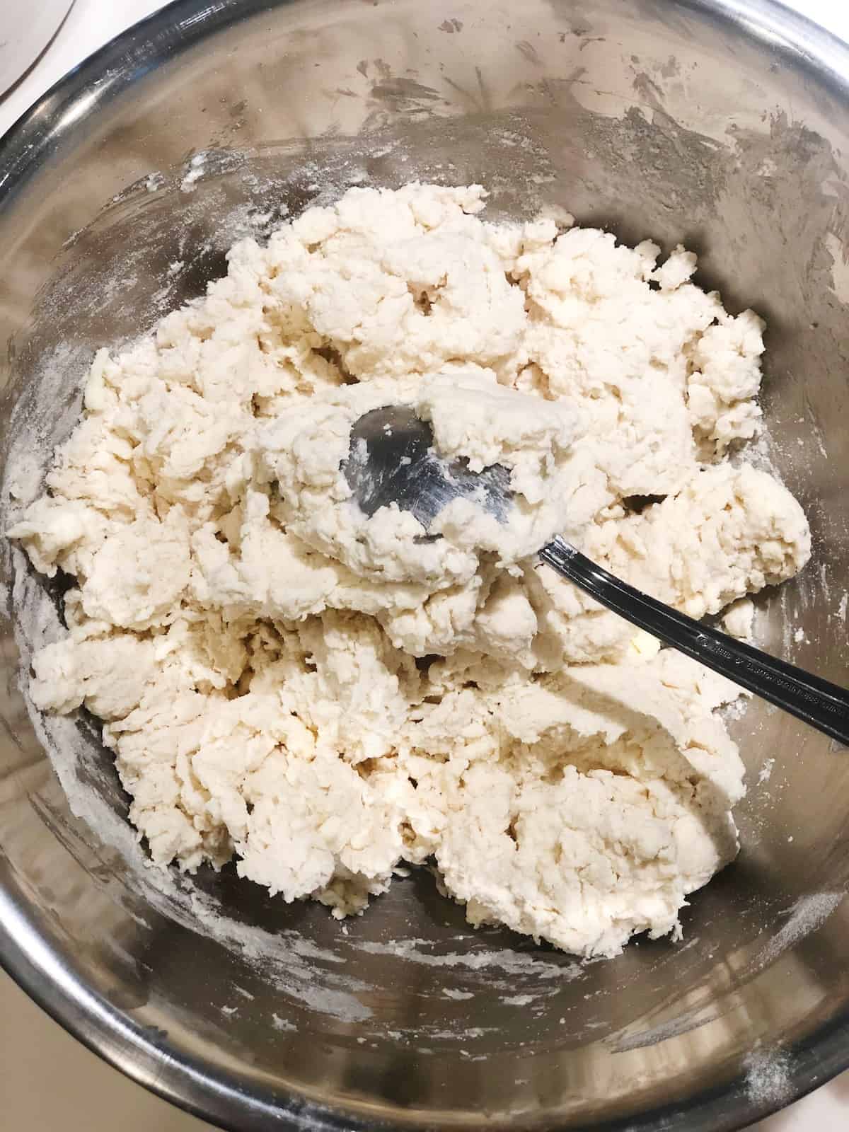 A bowl of dough with a spoon in it.
