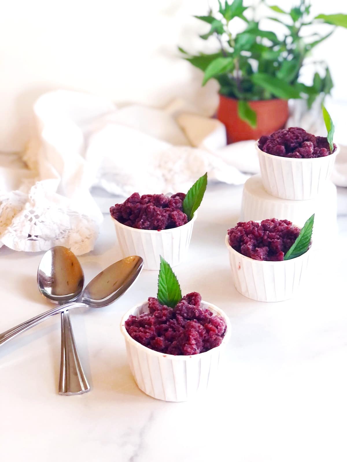 Four small bowls of cherry granita  on a marble table.
