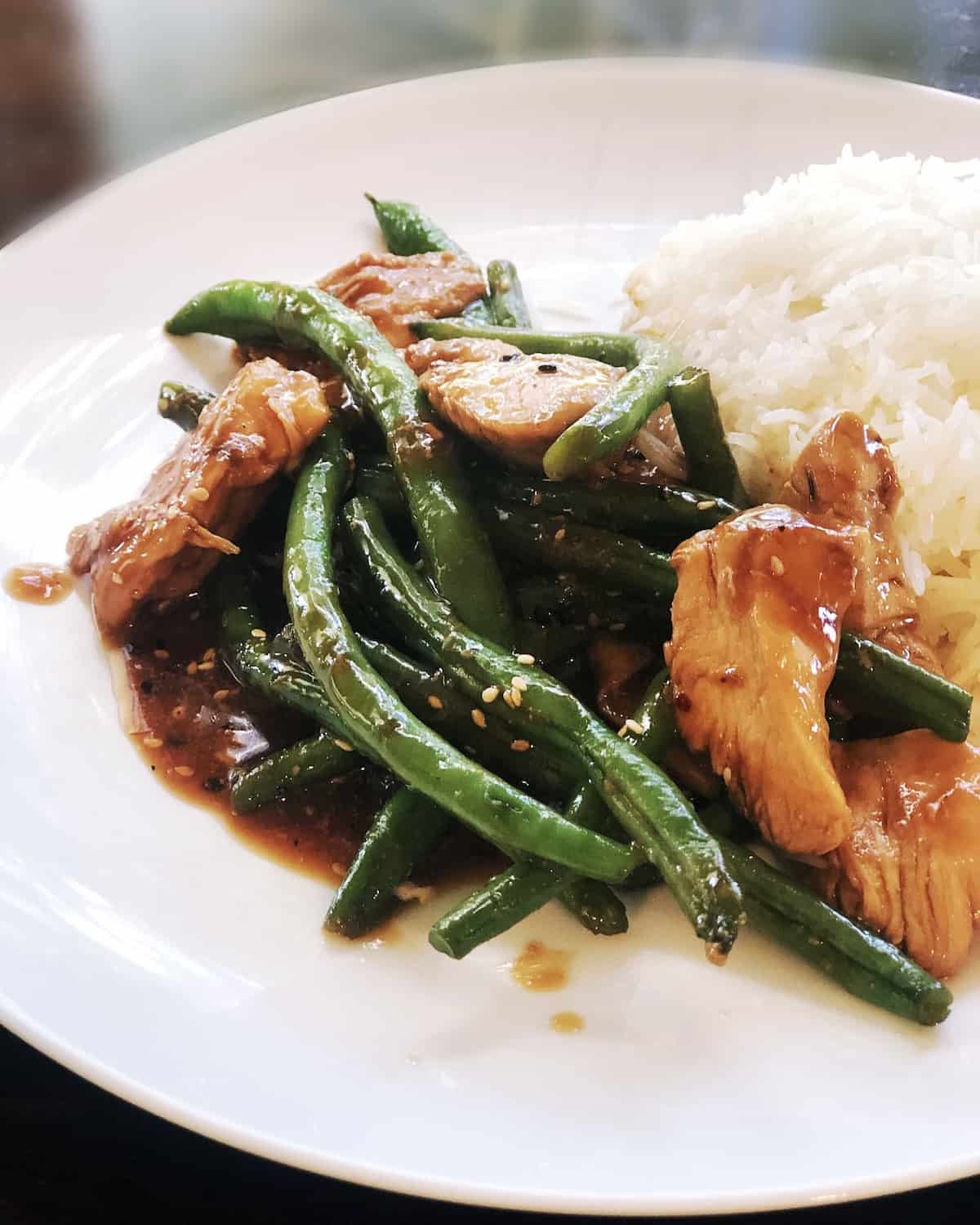 A white plate with chicken, green beans and rice.
