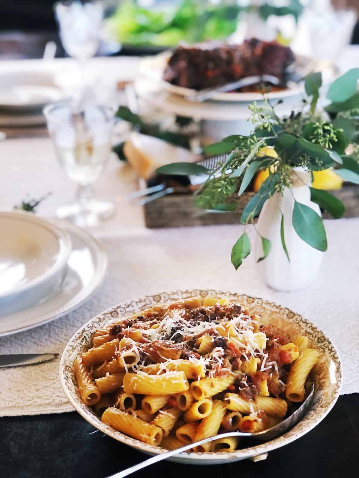 A bowl of pasta with meat and vegetables on a table.