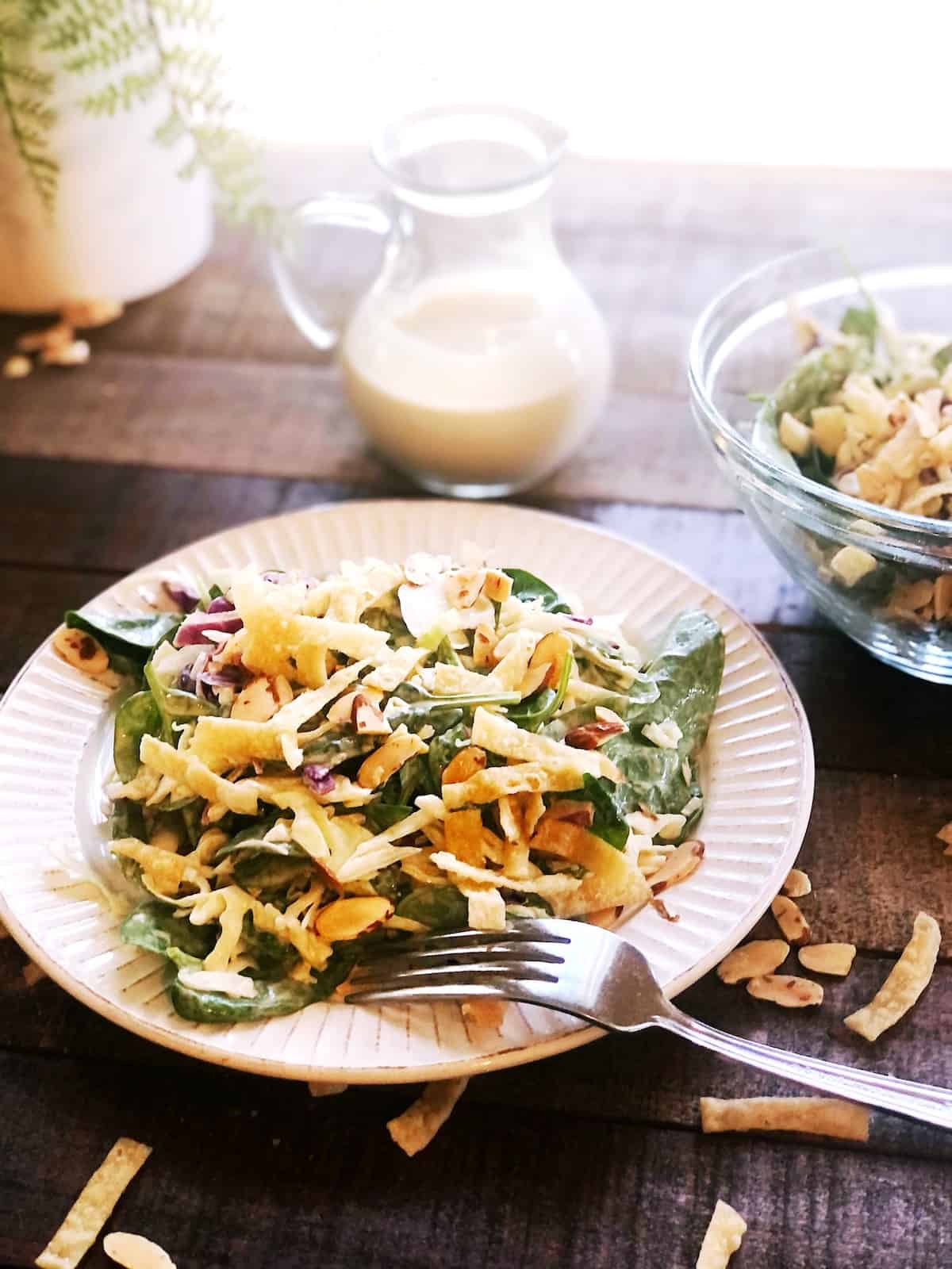 A plate with a salad and dressing on the table.