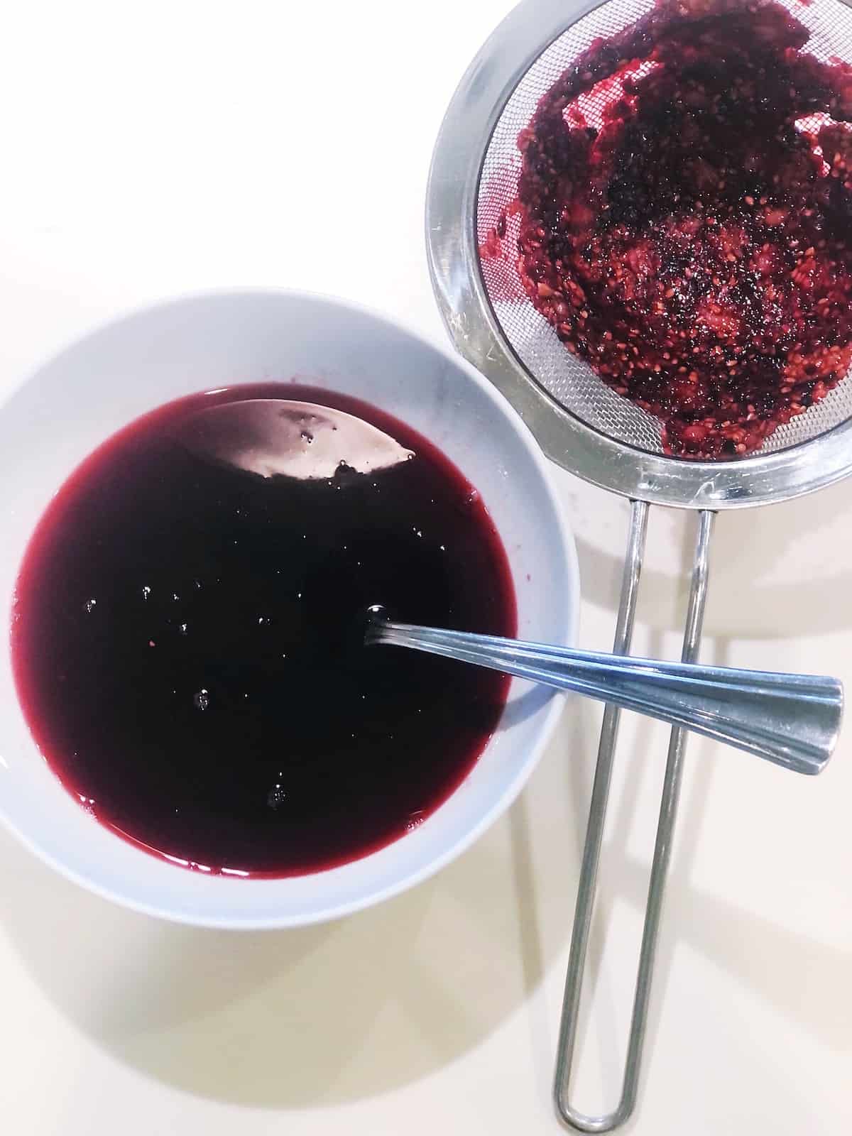 A bowl of berry sauce with a spoon next to it.