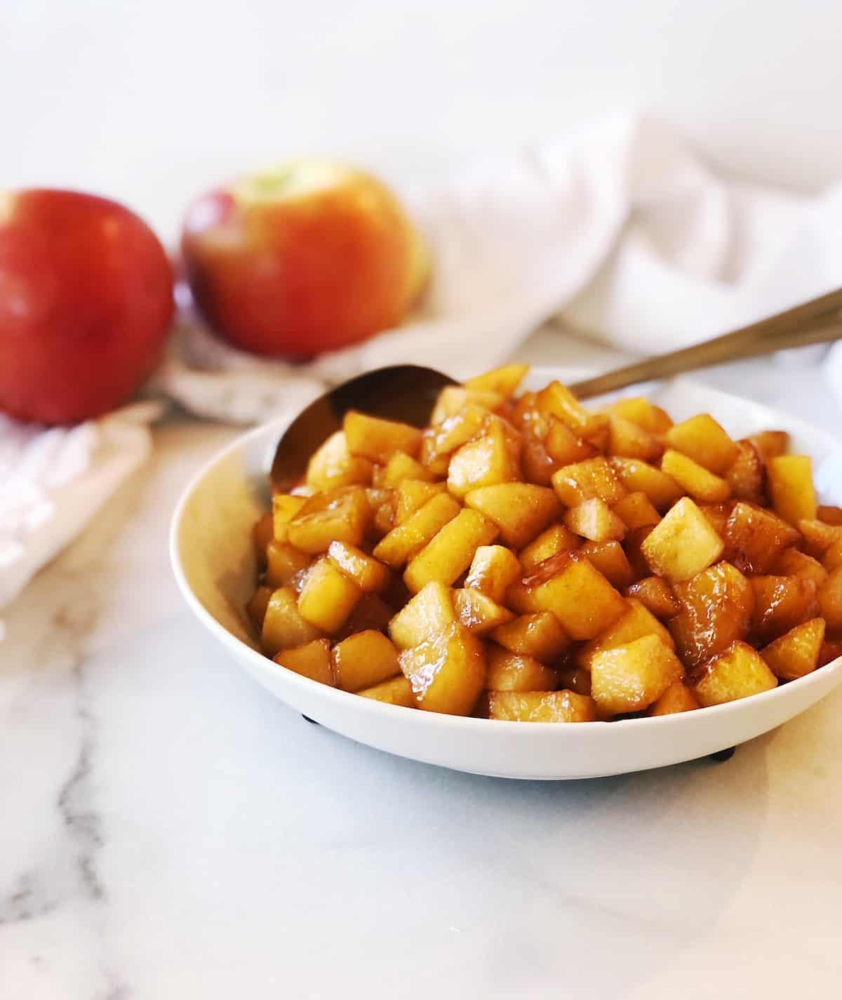 Apples in a bowl with a spoon.