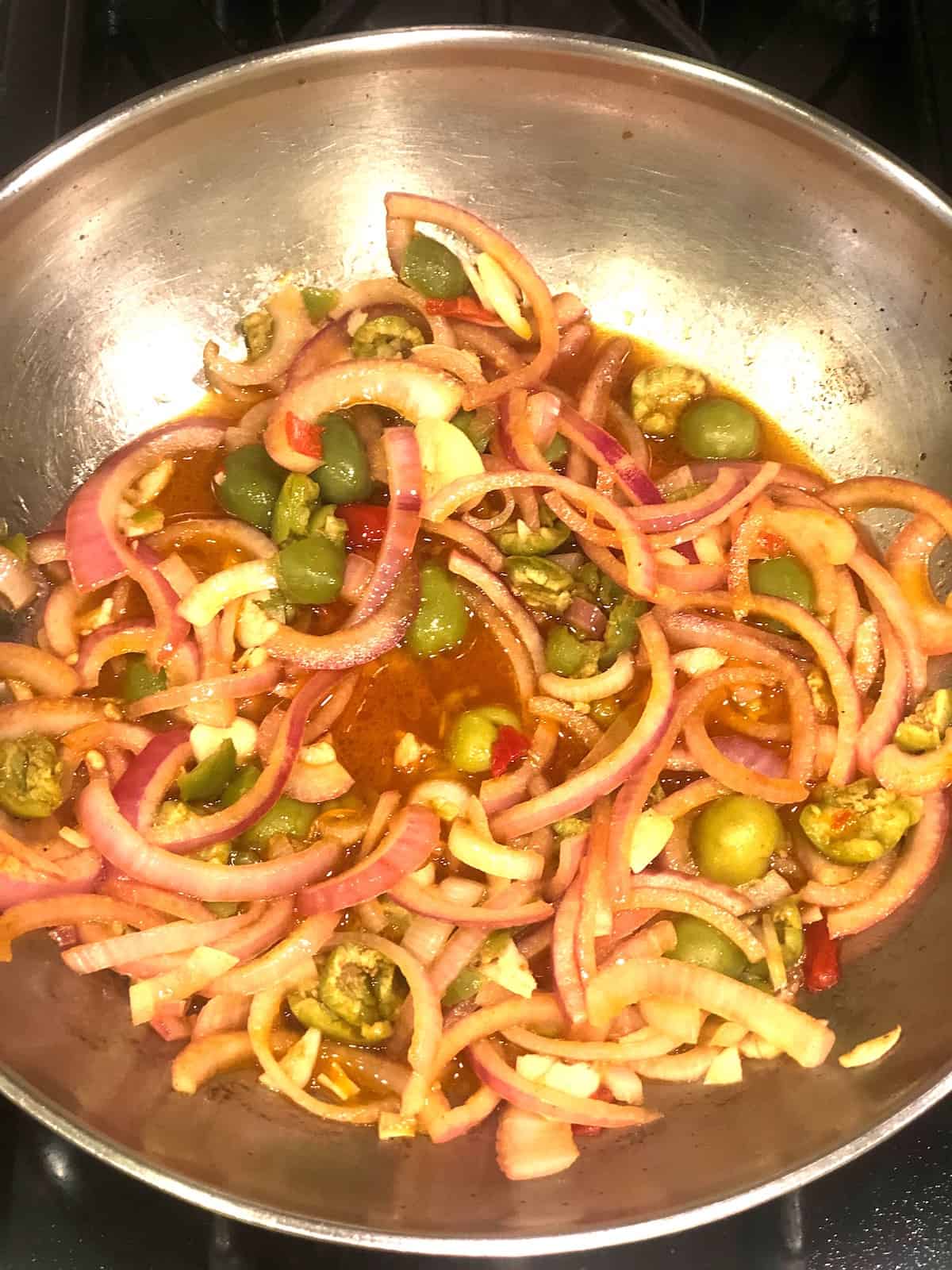 A pan full of onions and olives cooking on a stove.