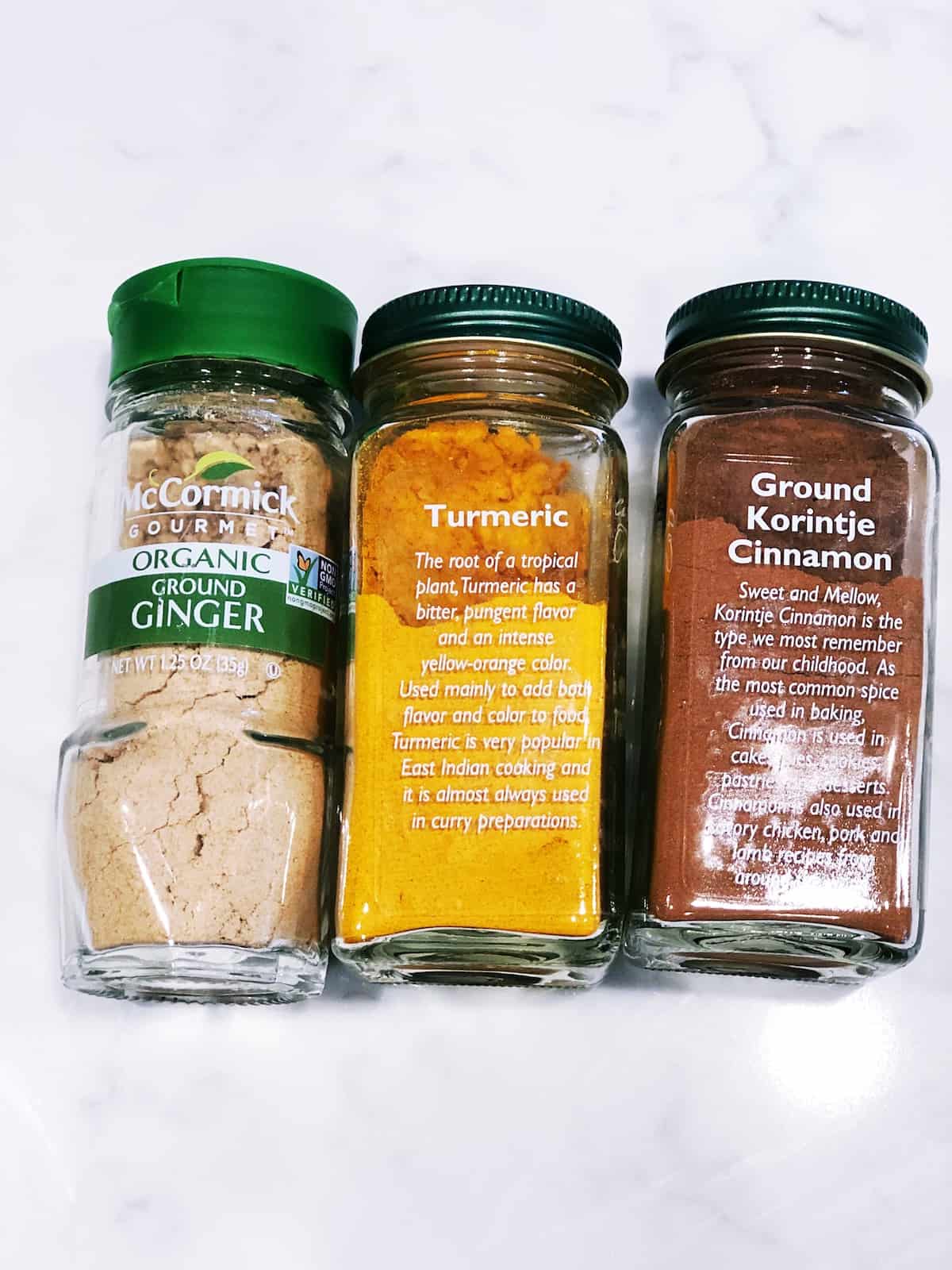 Three jars of spices on a marble countertop.