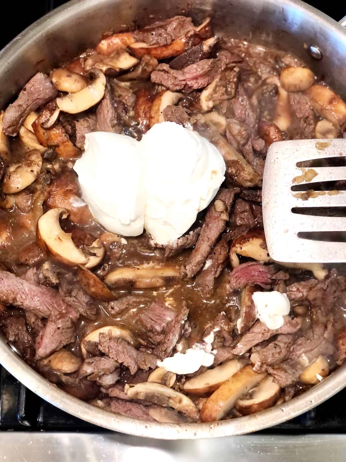 A pan with prime rib, mushrooms and sour cream.