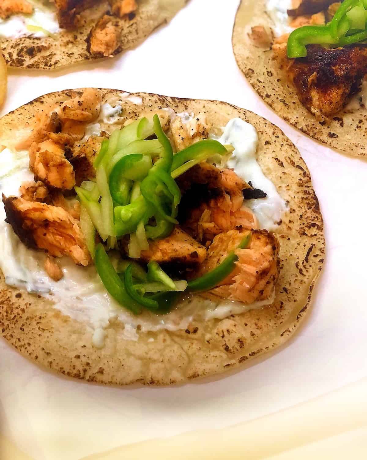 Blackened salmon tacos with yogurt sauce and pickled hot peppers.