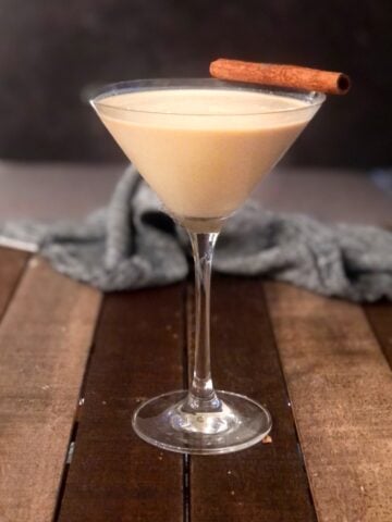 A baileys and eggnog cocktail with a cinnamon stick on top.