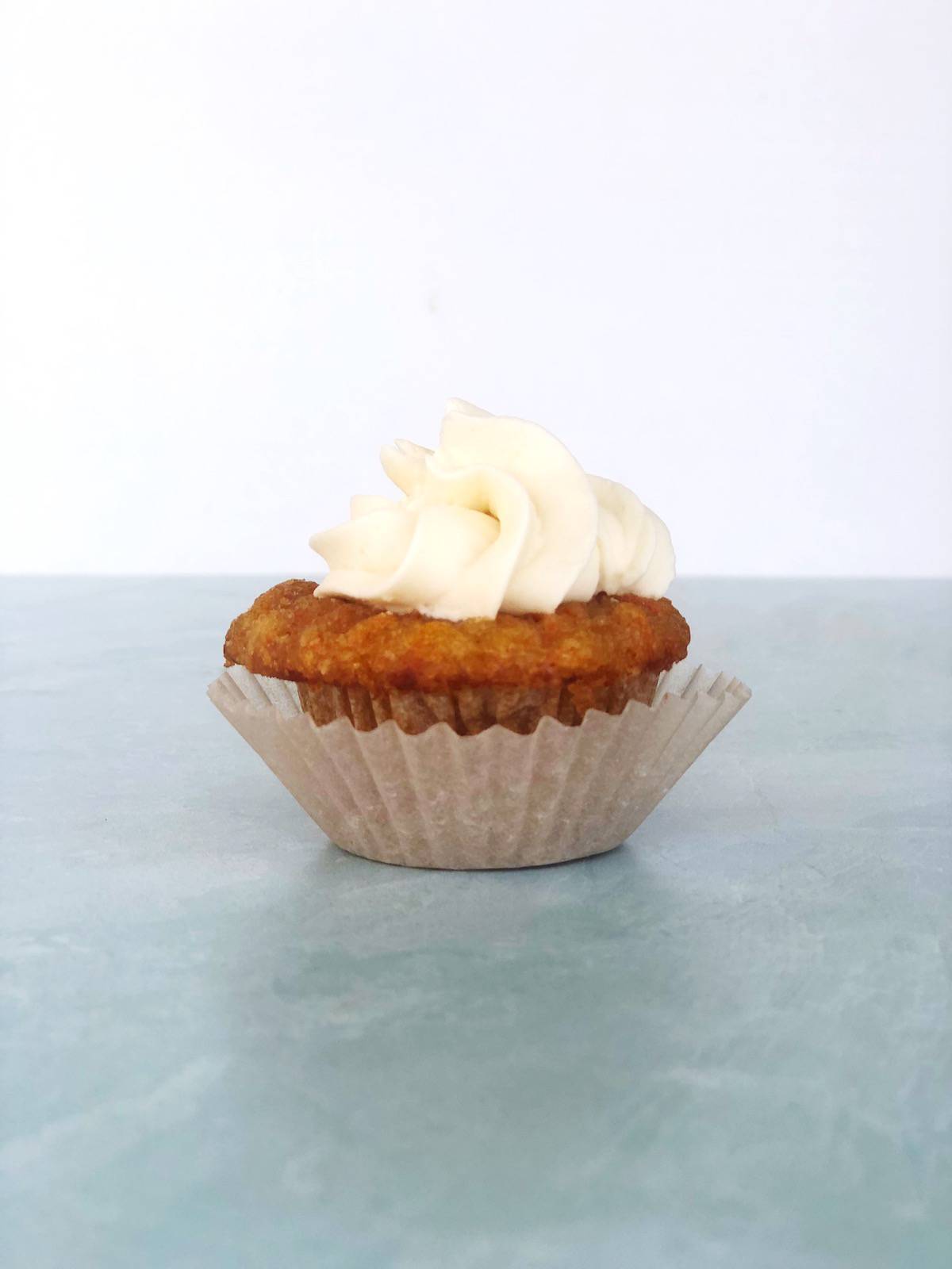 A carrot cake cupcake with cream cheese frosting on top.