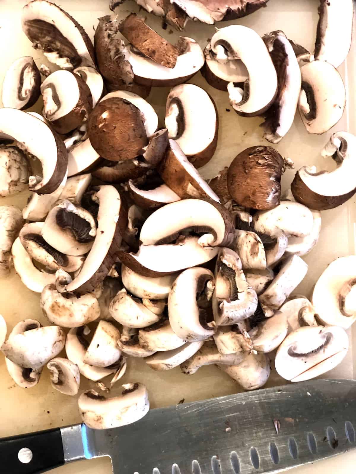 A knife on a cutting board with mushrooms on it.