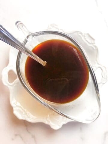 A bowl of sauce with a spoon in it.