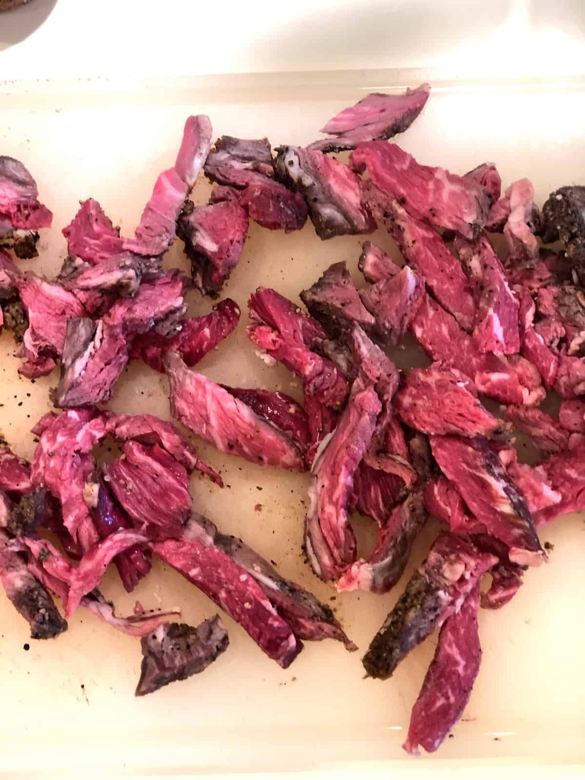 A cutting board with prime rib on it.