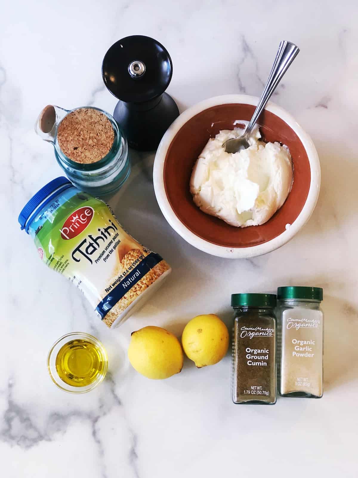 The ingredients for tahini yogurt sauce on a marble table.