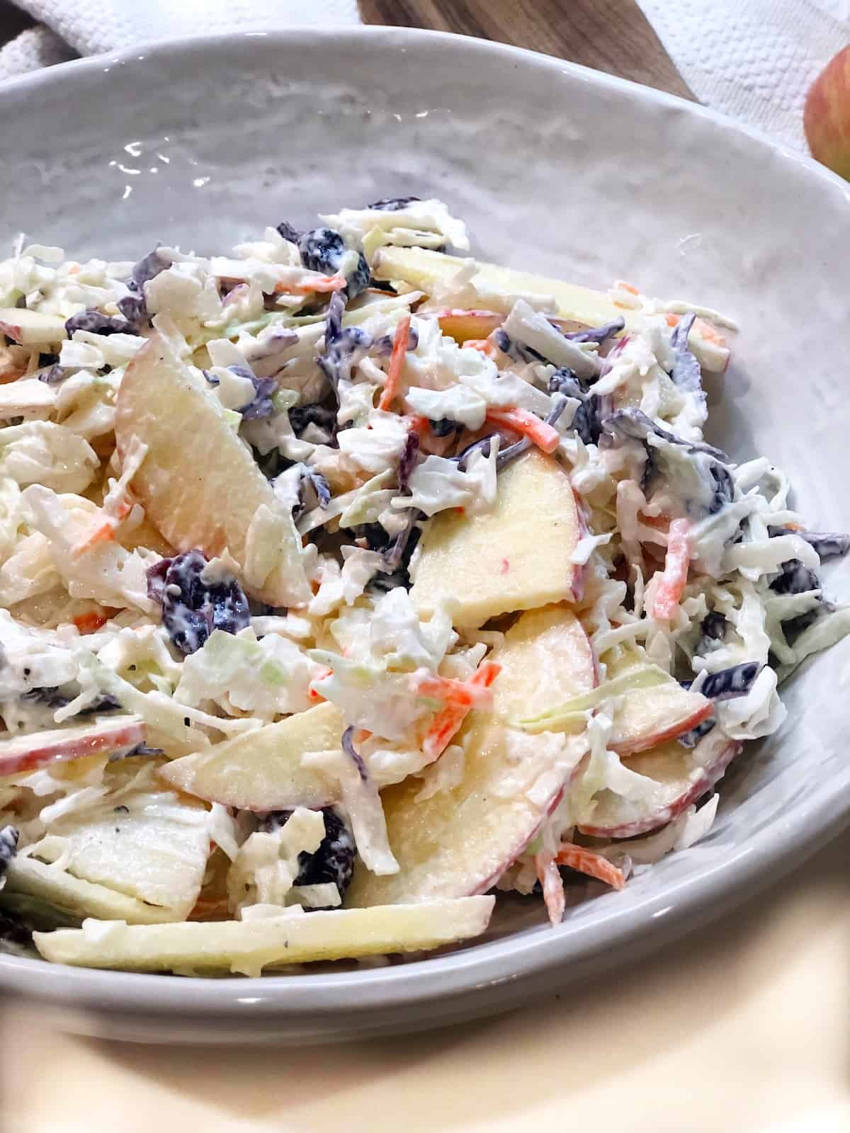 A closeup view of healthy Apple Cranberry Coleslaw in a large bowl on the counter.