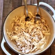 Shredded chicken in a Dutch oven with two forks.