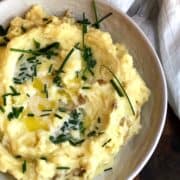 Yukon Gold Mashed Potatoes in a large bowl on a wood board.