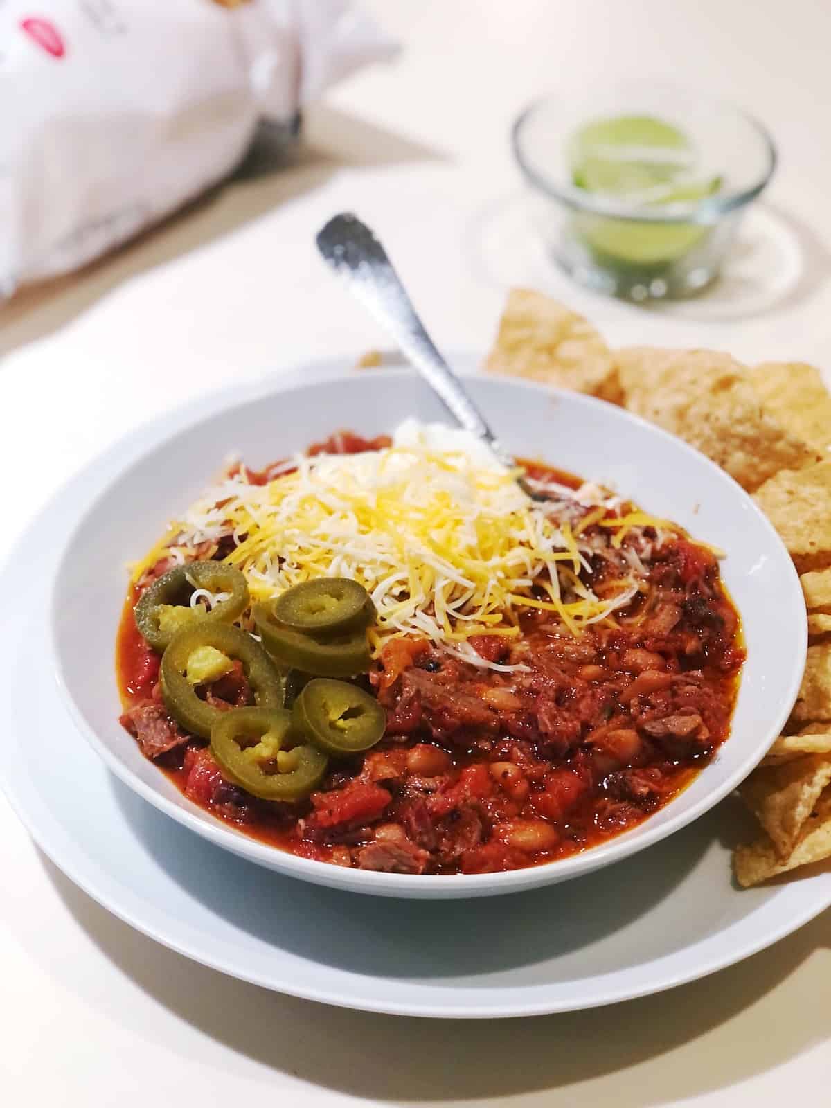 Brisket chili in a bowl with tortilla chips on the side.