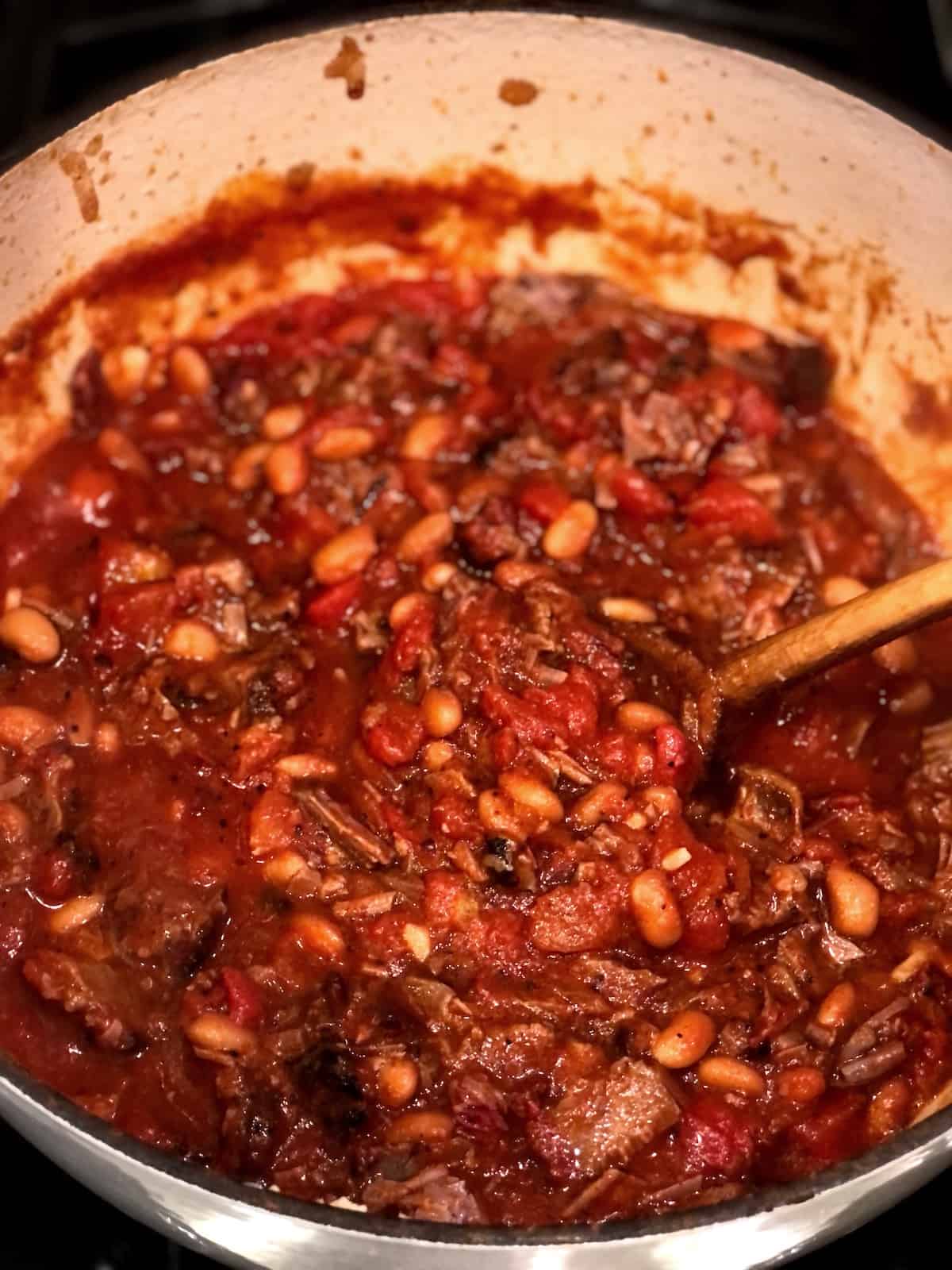 stirring brisket chili in a large pot