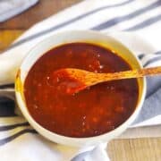 Cherry BBQ sauce in a bowl on a wood board.