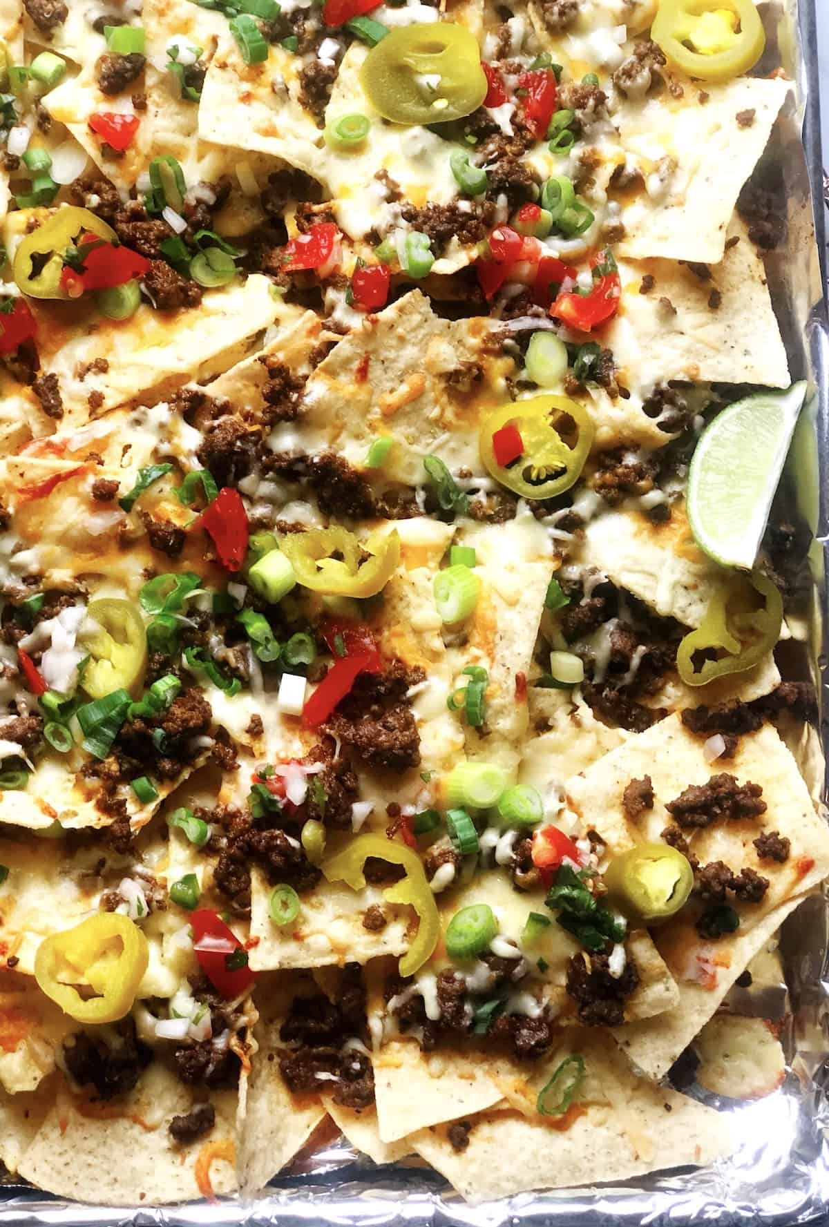 closeup of ground beef nachos with toppings on top.