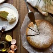 Basil olive oil cake on the counter sliced up with a slice on a plate.
